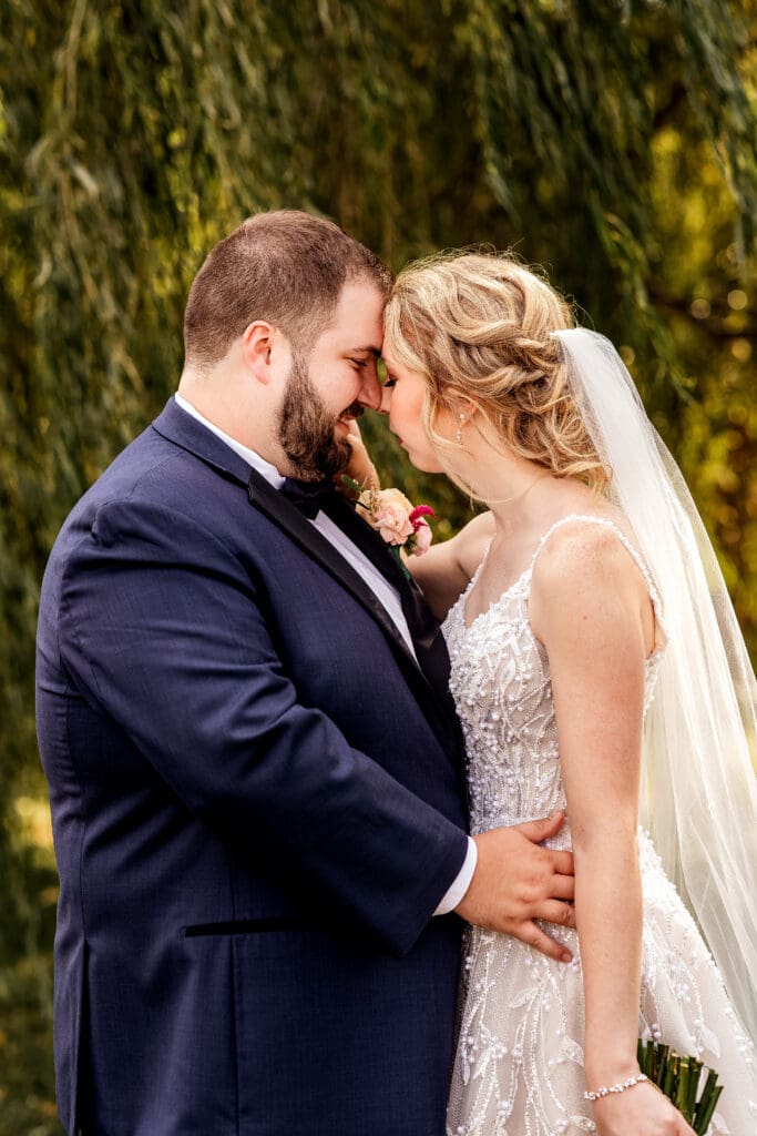 Wedding couple embracing under a willow tree during portraits at The Gathering Place at Darlington Lake