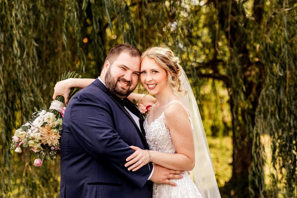 Wedding couple posing together beneath willow tree at The Gathering Place at Darlington Lake