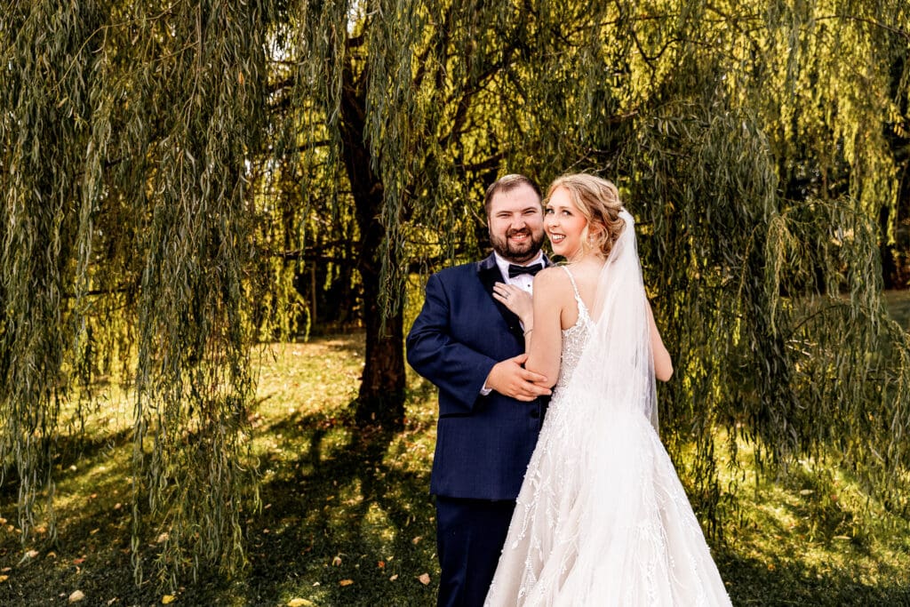 Wedding couple posing together beneath willow tree at The Gathering Place at Darlington Lake