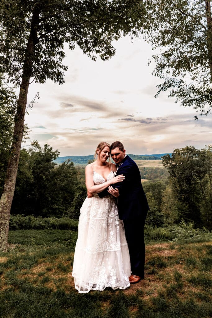 Bride and groom snuggling together in front of the overlook at sunset at The Barn at Ever Thine in Fenelton, Pennsylvania