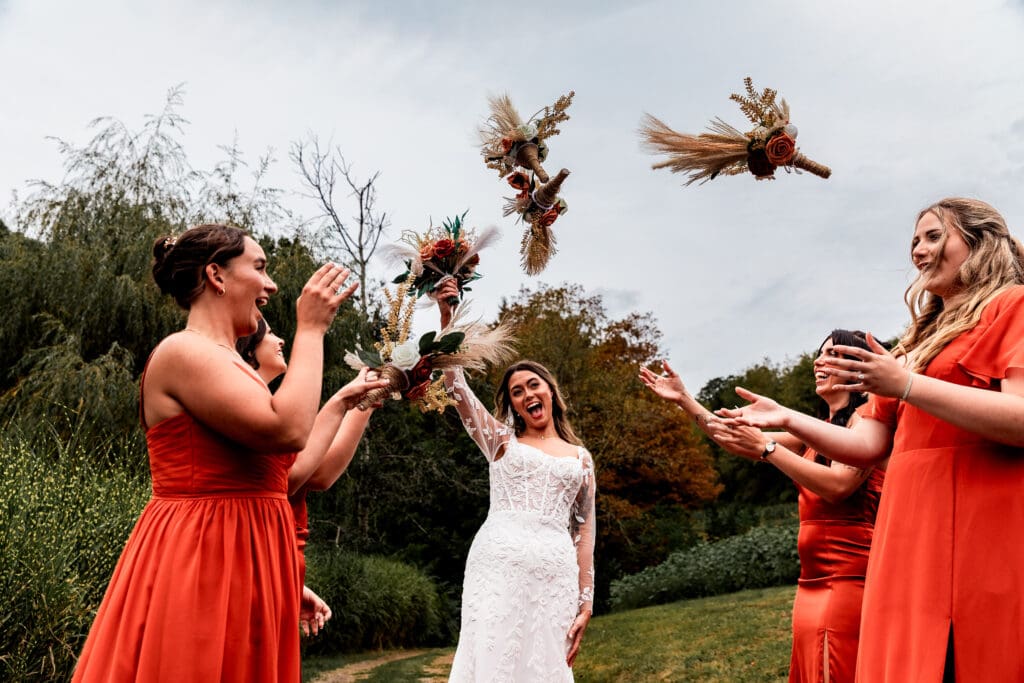Wedding party in terracotta dresses celebrating joyfully in outdoor garden at Hinckston Run Farm