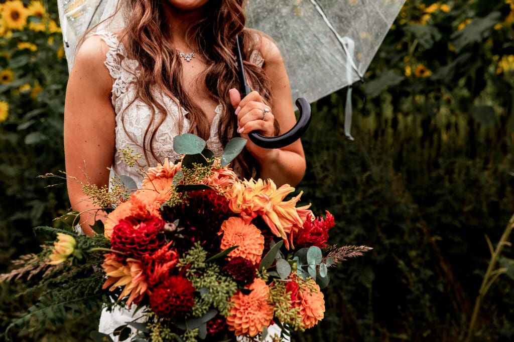 Orange and burgundy dahlia bouquet against sunflower backdrop at Hinckston Run Farm