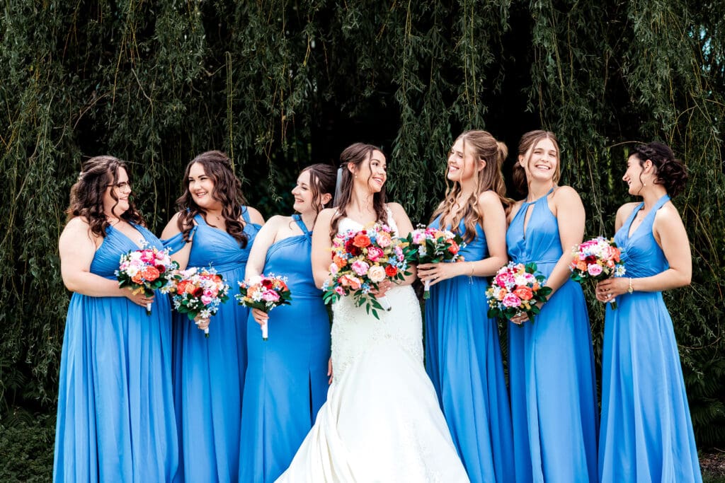 Bride in white gown poses with bridesmaids in blue dresses during a Willowbrook wedding