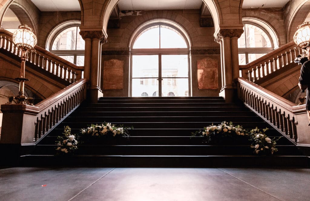 Elegant white wedding floral arrangements displayed on the grand staircase of Allegheny County Courthouse