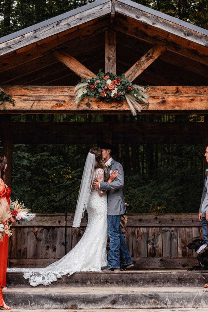 First kiss captured in rustic wooden pavilion surrounded by forest at Hinckston Run Farm