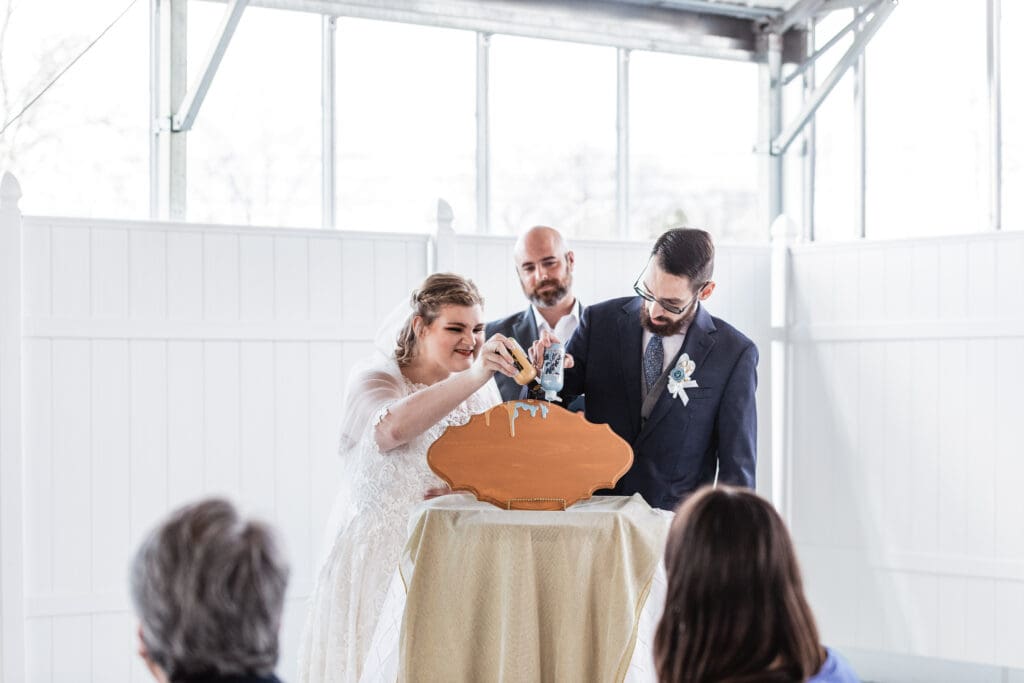 Wedding couple creates a paint drip decor piece during their unity ceremony at The Atrium
