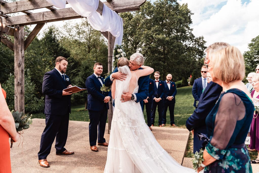 Father and daughter sharing a hug during the wedding ceremony at The Barn at Ever Thine in Fenelton, PA