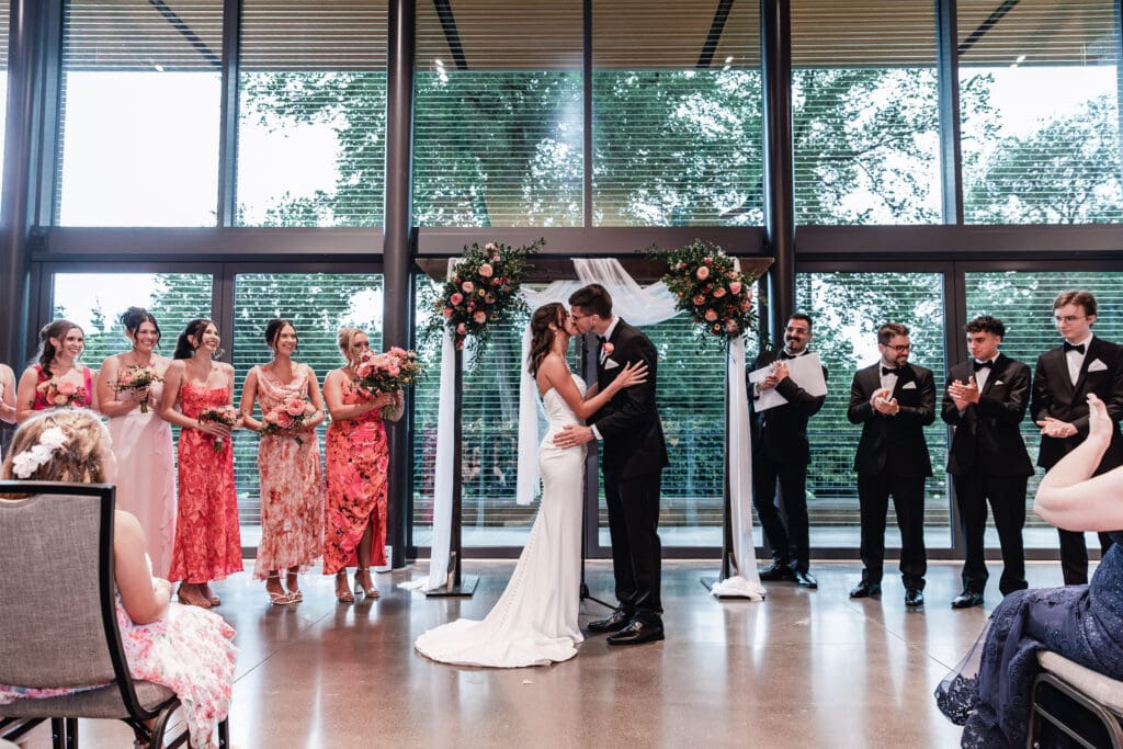 Bride and groom sharing their first kiss during wedding ceremony at the National Aviary