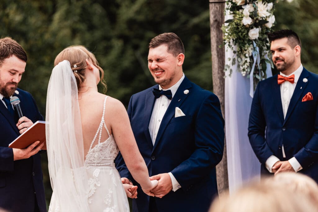 Groom laughing with his bride during their wedding ceremony at The Barn at Ever Thine in Fenelton, PA