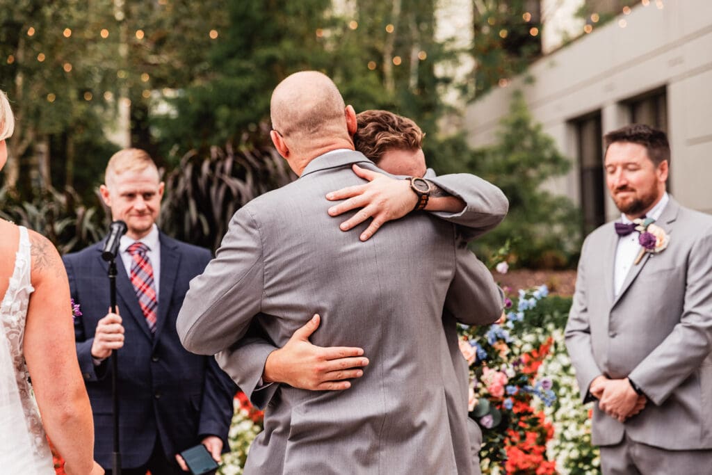 Pittsburgh groom embraces his father-in-law at the altar during Pittsburgh Airport Marriott ceremony