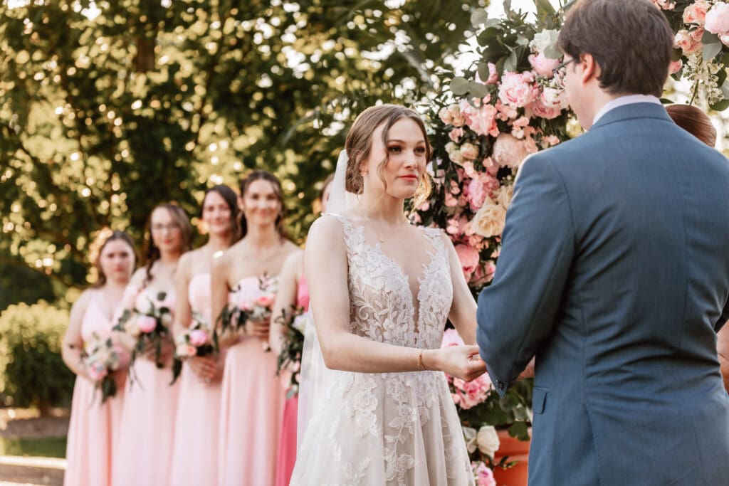 Bride looking at her groom as she places his wedding band on his finger during a Phipps Botanical Gardens wedding