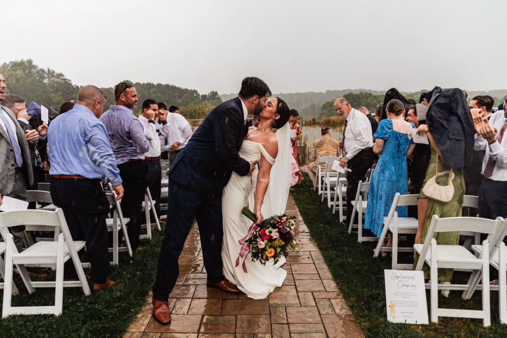 Bride and groom dip kiss mid-aisle during their Willowbrook wedding ceremony in Volant, Pennsylvania
