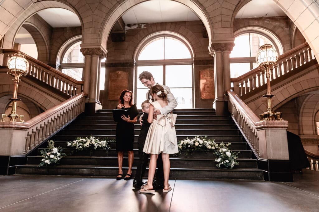 Flower girl and ring bearer hugging their stepdad during an Allegheny County Courthouse wedding ceremony