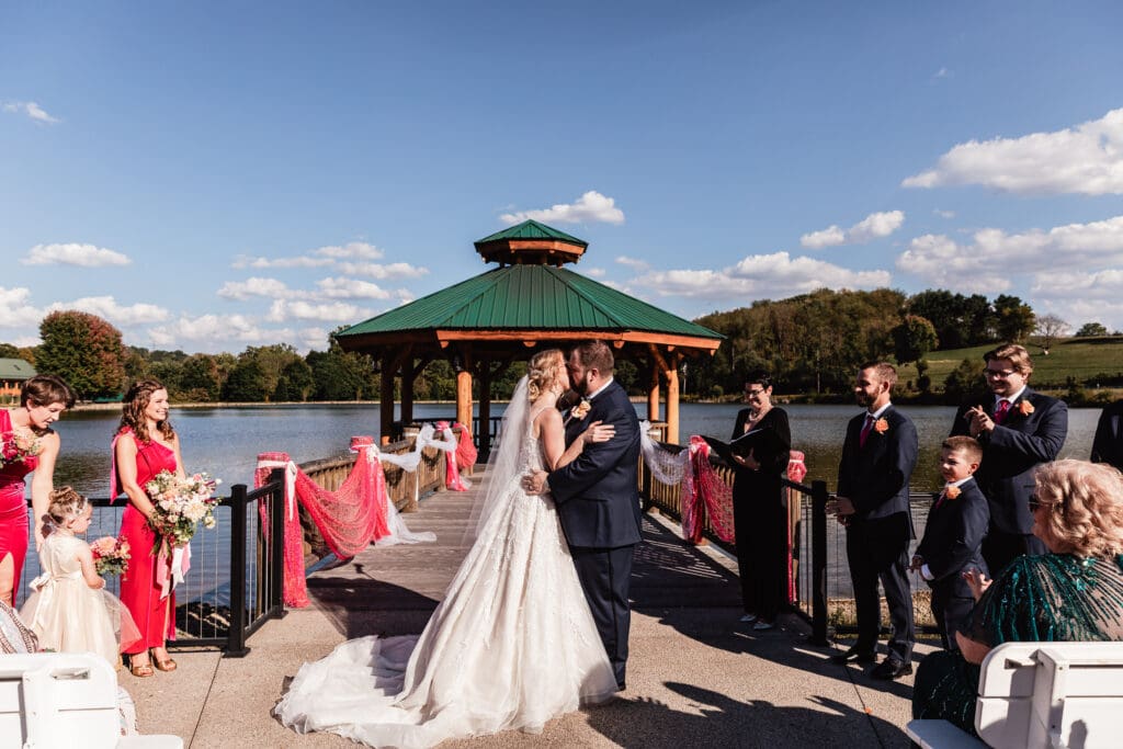 Bride and groom sharing their first kiss during ceremony at The Gathering Place at Darlington Lake