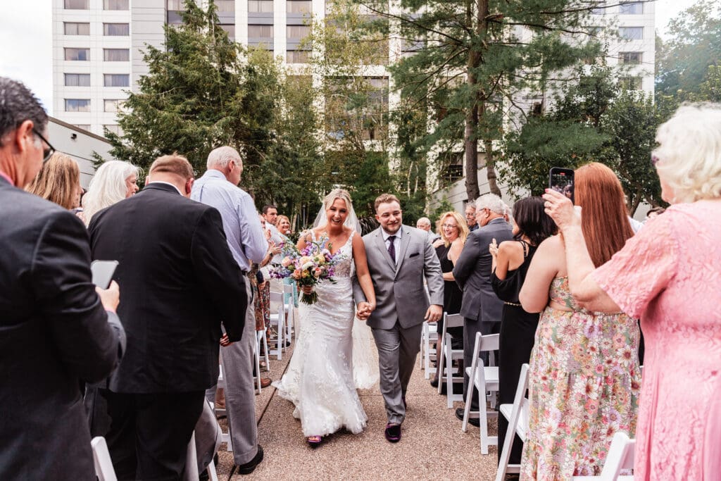 Bride and groom walk down the aisle hand in hand after ceremony at Pittsburgh Airport Marriott