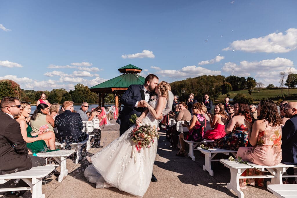 Wedding guests blowing bubbles as couple walks down aisle at The Gathering Place at Darlington Lake