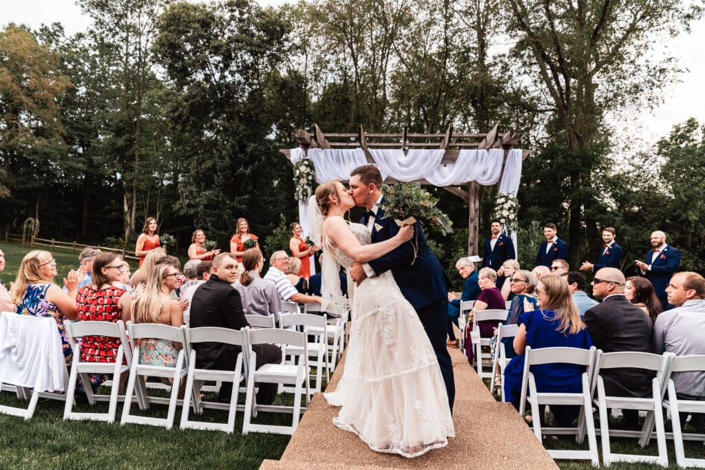 Bride and groom sharing a dip kiss during their wedding ceremony at The Barn at Ever Thine in Butler County, PA