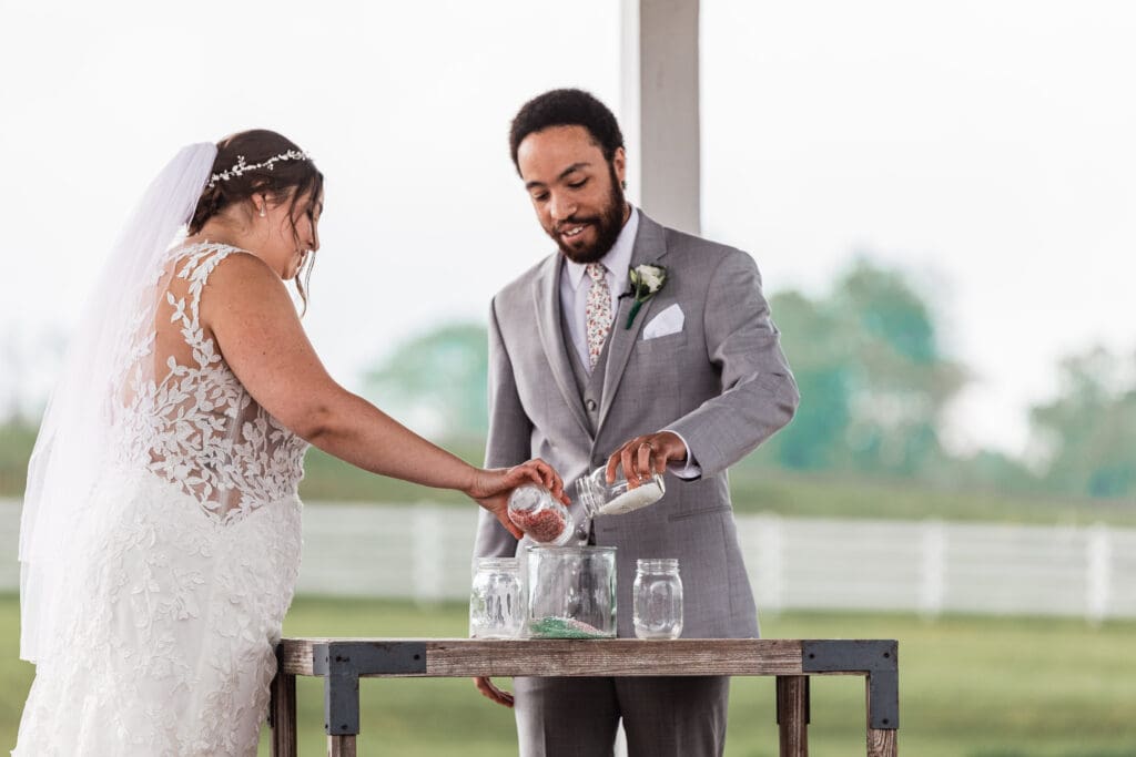Wedding couple pours colored glass into a bowl for a unity ceremony at Lingrow Farm