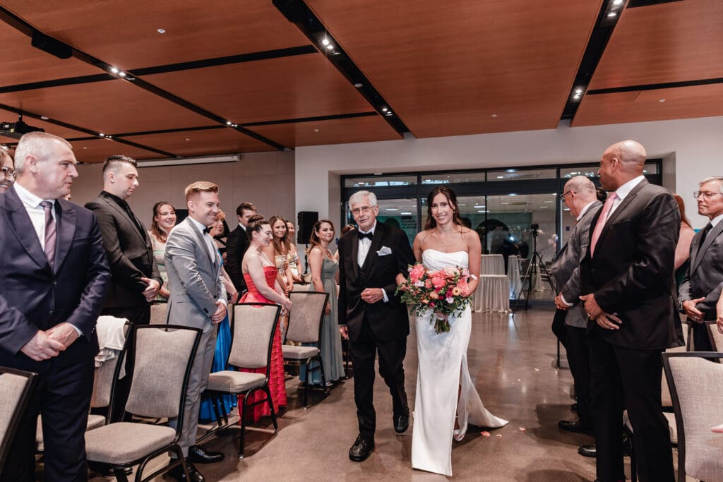 Bride walking down the aisle with her father at wedding ceremony at the National Aviary