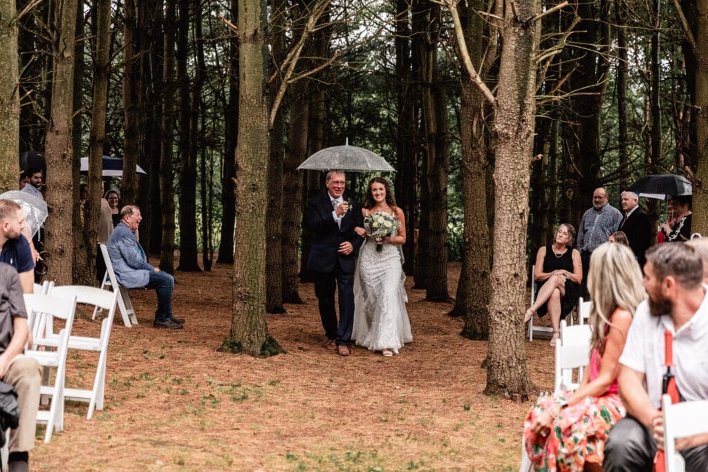 Bride walking down the aisle with her father under umbrellas at Sanaview Farm wedding in Somerset, Pennsylvania