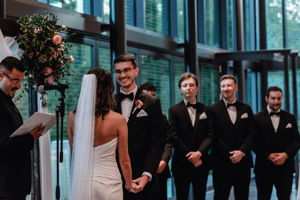 Groom smiling at his bride during wedding ceremony at the National Aviary