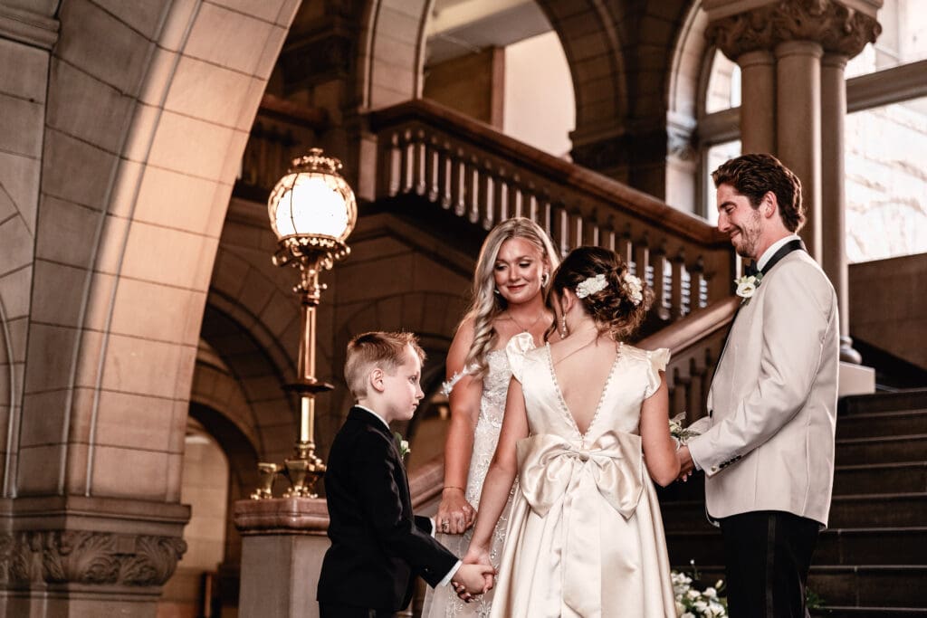 Blended family holding hands during an intimate wedding ceremony at Allegheny County Courthouse