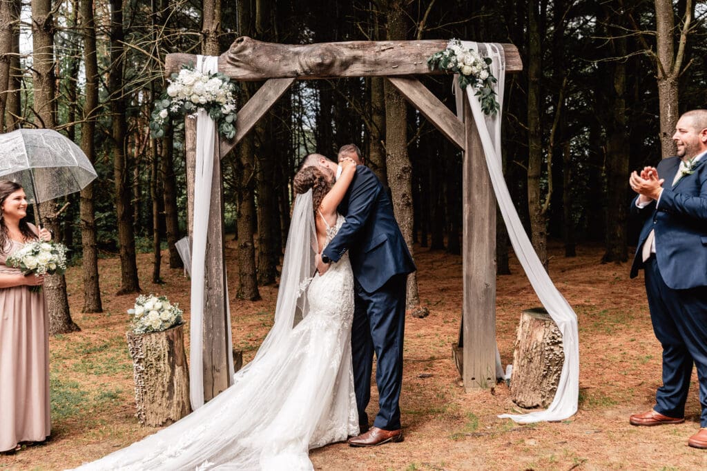 Bride and groom sharing their first kiss as the sun breaks through the clouds at Sanaview Farm wedding in Somerset, PA