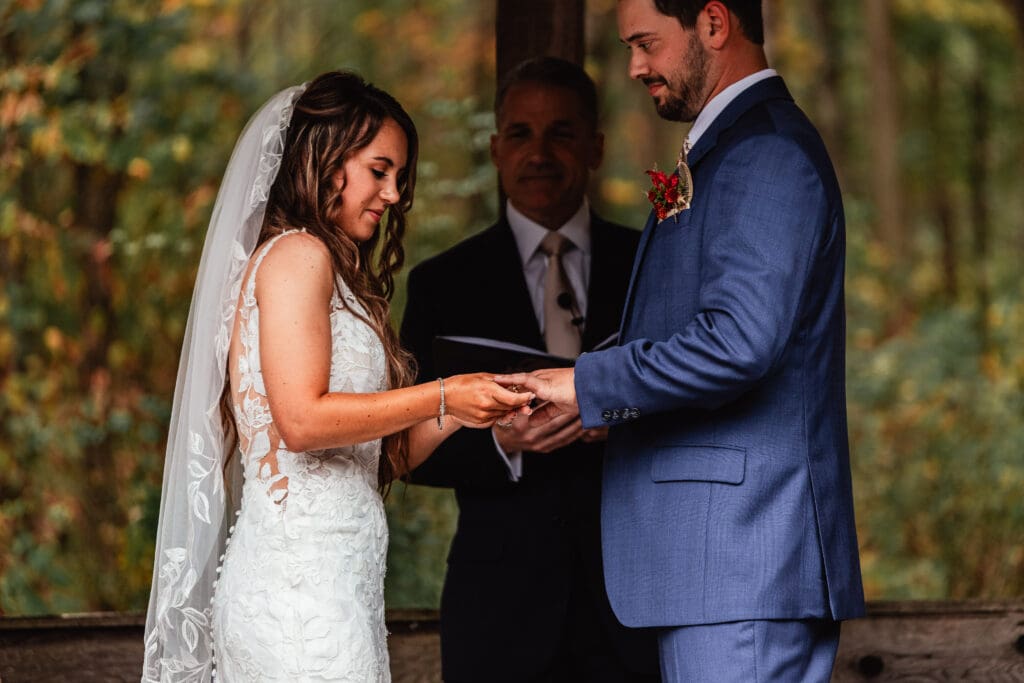 Couple exchanges rings during outdoor autumn ceremony at Hinckston Run Farm