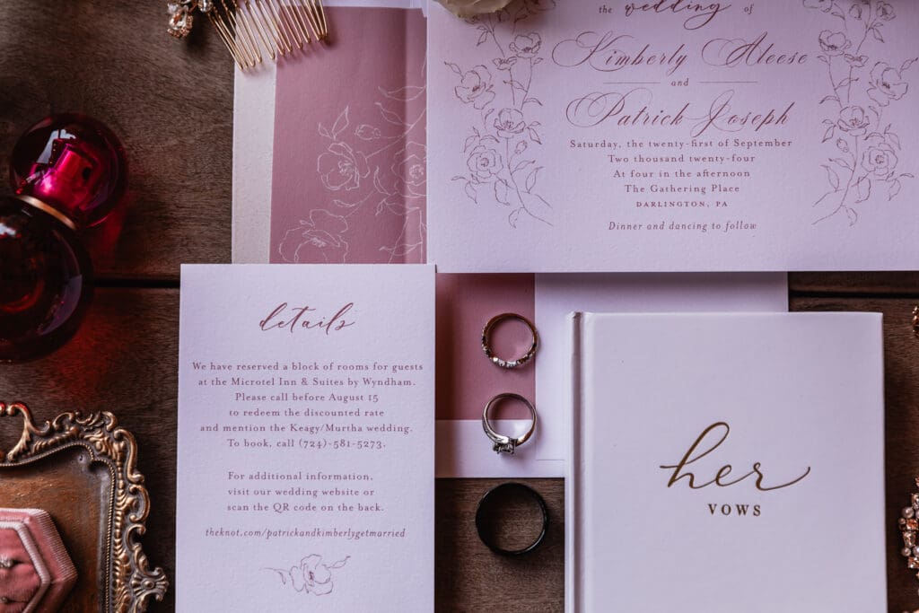 Wedding detail flat lay featuring invitations, vows, and wedding bands at The Gathering Place at Darlington Lake