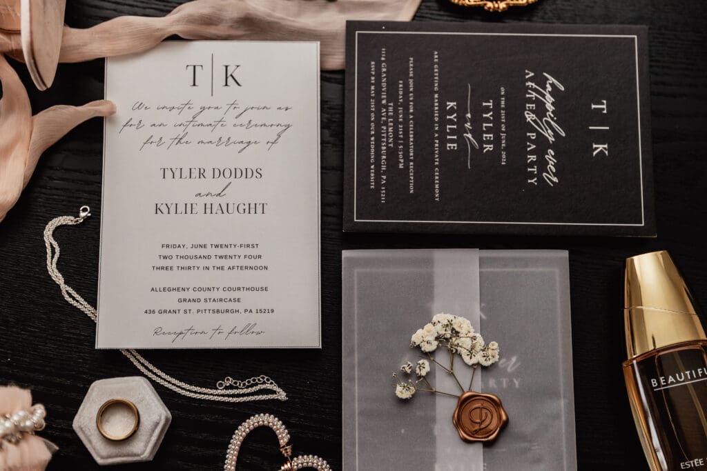 Close-up flat lay of wedding invitation, rings, and perfume for an intimate Pittsburgh wedding