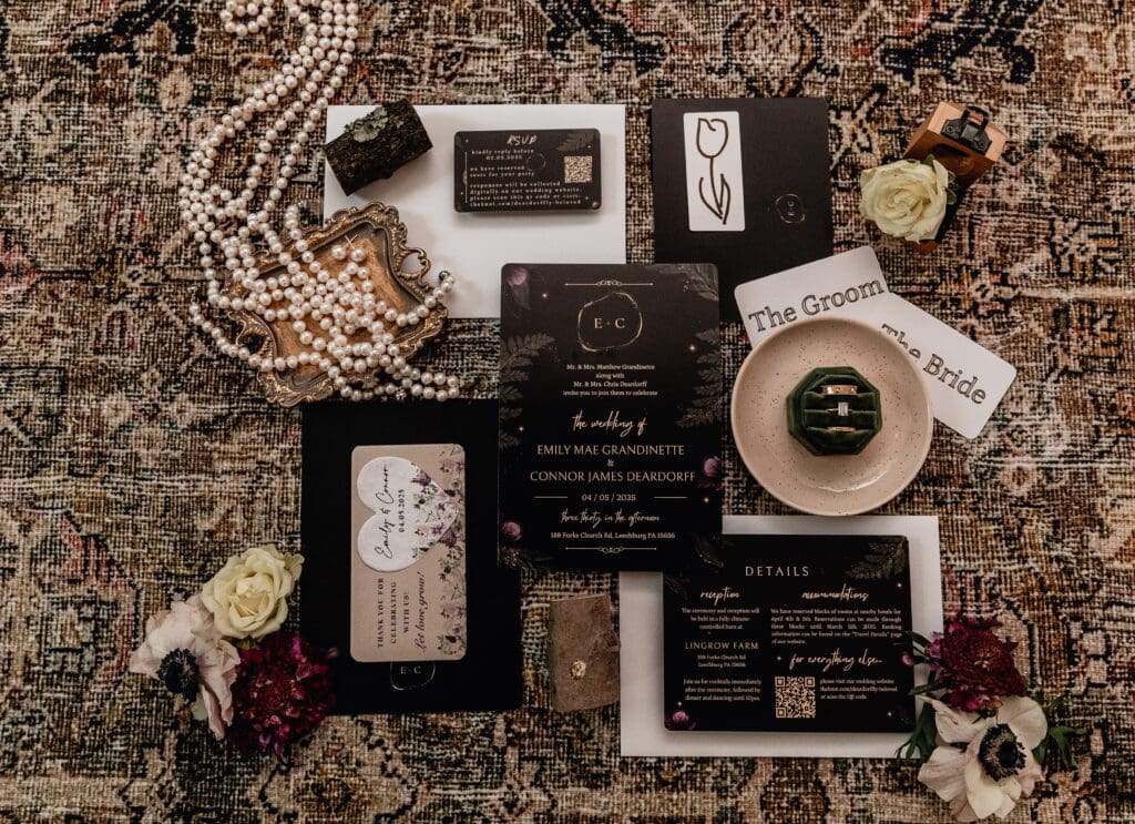 Romantic wedding flat lay with invitation suite, pearl necklace, florals, place cards, RSVP card, and green velvet ring box styled on a vintage rug at Lingrow Farm