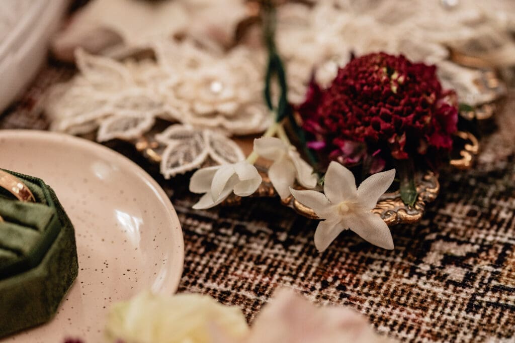 Flat lay of embroidered bridal lace, purple and cream flowers, gold tray styled for a Lingrow Farm wedding