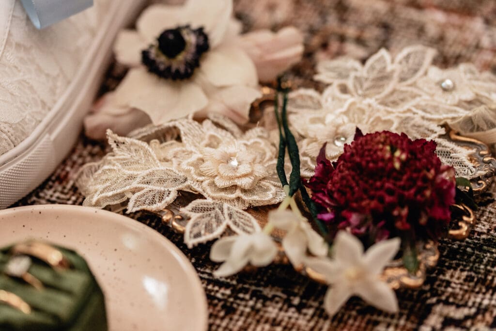 Delicate wedding flat lay with lace details, red and white florals, and gold tray styled for a Lingrow Farm wedding