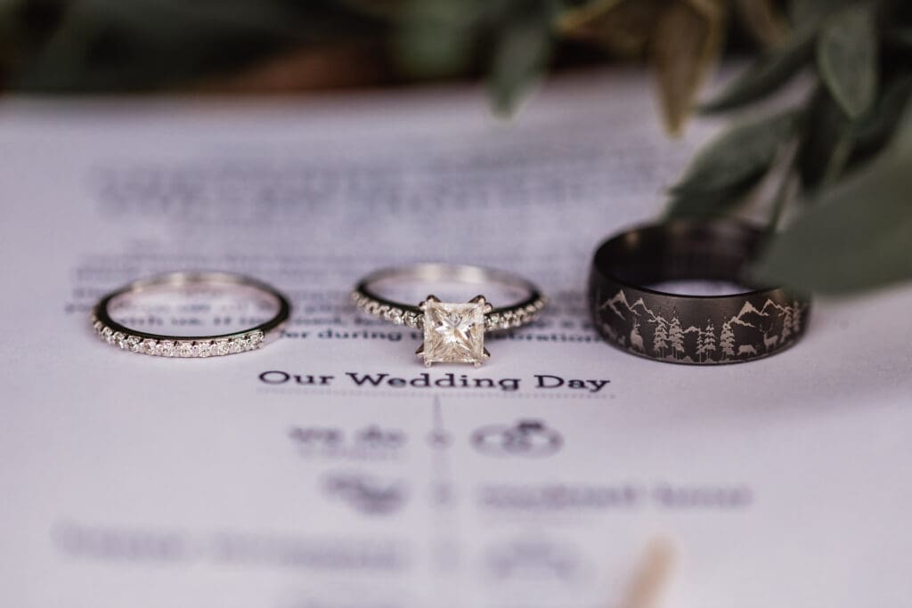 Close-up of wedding bands and engagement ring resting on a wedding program at The Barn at Ever Thine wedding reception in Fenelton, Butler, PA