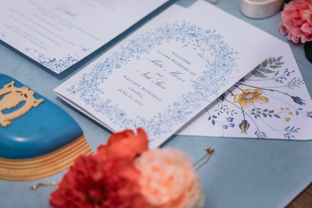 Wedding greeting cards with calligraphy and coral florals displayed flat lay