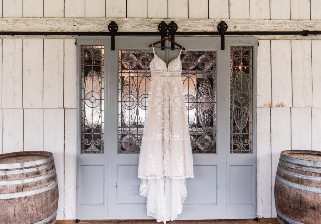 Wedding dress hanging on a sliding blue stained-glass barn door at The Barn at Ever Thine in Butler County, PA