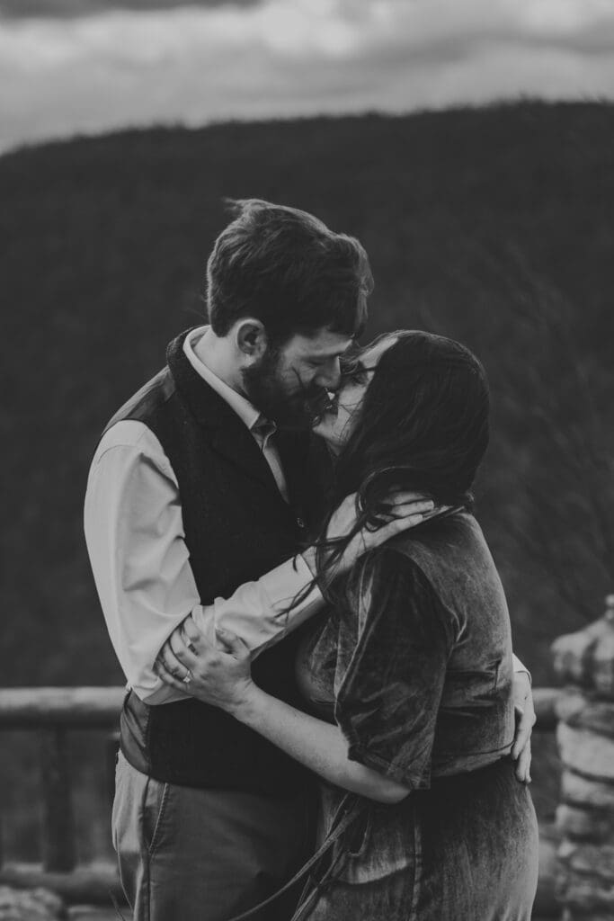 Black and white engagement photo of a couple kissing at Coopers Rock State Park