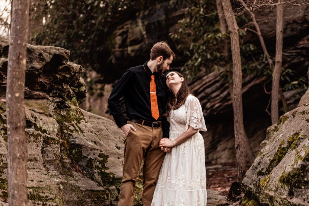 Couple holding hands and looking at each other while walking through the woods at Coopers Rock State Park