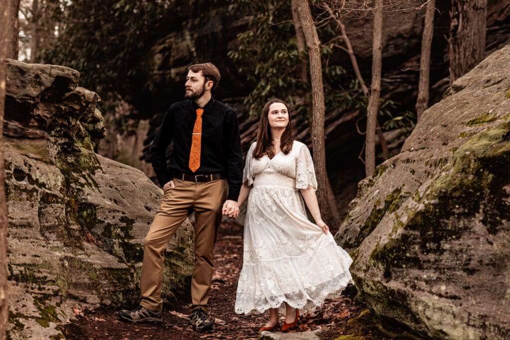 Engaged couple holding hands and looking in opposite directions during a scenic Coopers Rock engagement session