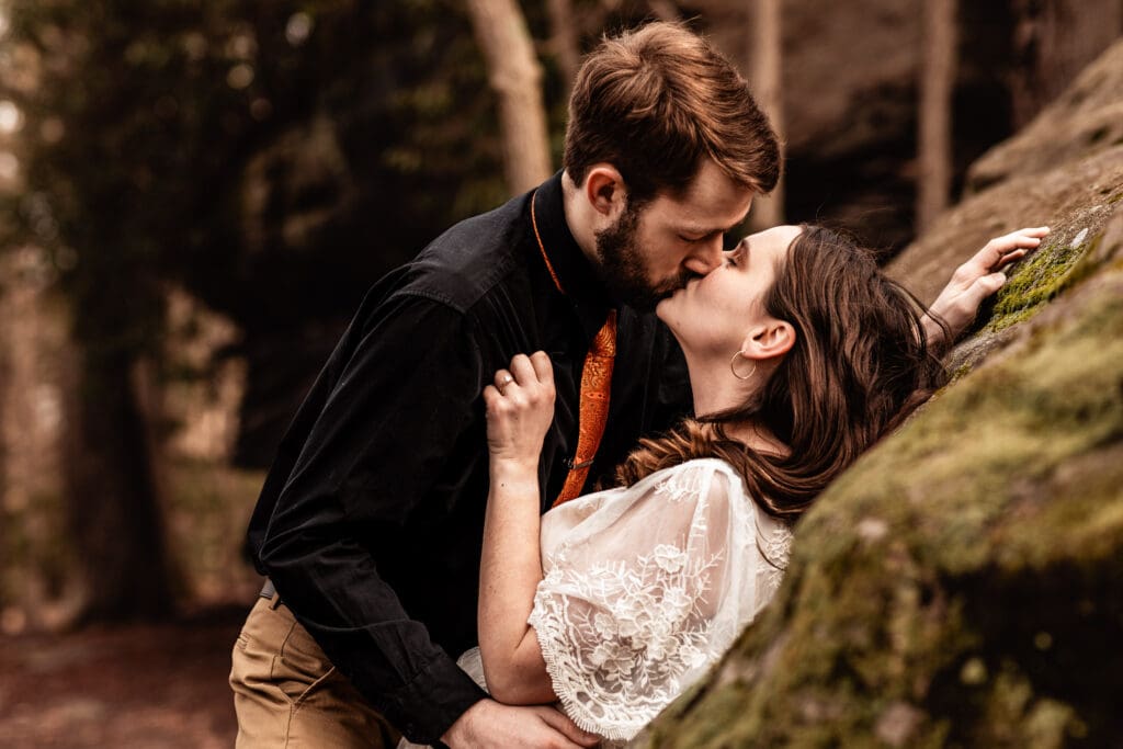 Groom leaning his fiancée against a rock and kissing her during a Coopers Rock engagement session