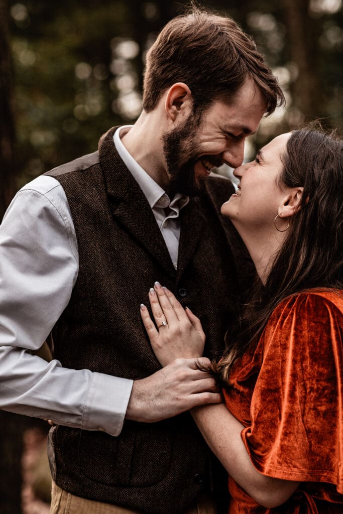 Couple laughing and looking at each other during a relaxed engagement session at Coopers Rock State Park