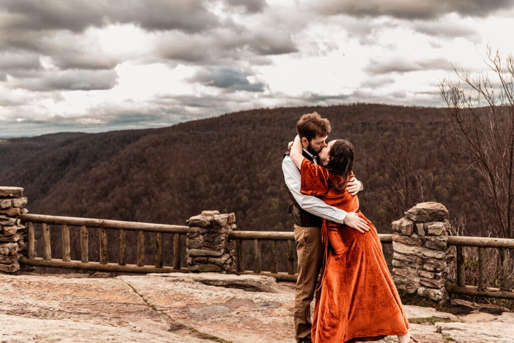 Bride-to-be falling into her fiancé’s arms during a playful engagement session at Coopers Rock State Park