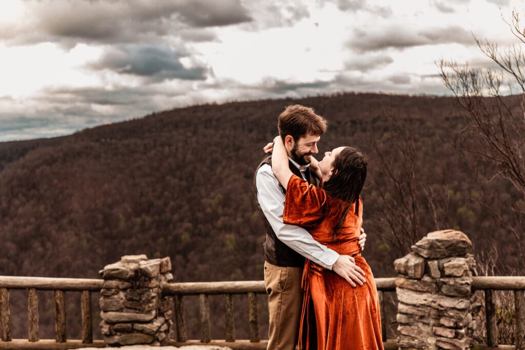 Close-up moment of a bride-to-be laughing as she falls into her fiancé’s arms at Coopers Rock State Park