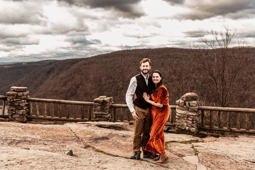 Engaged couple resting their heads together as the wind moves through the overlook at Coopers Rock State Park