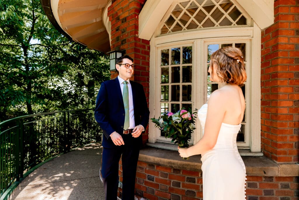 Groom wiping away tears as he sees his bride for the first look at Schenley Park Welcome Center in Oakland