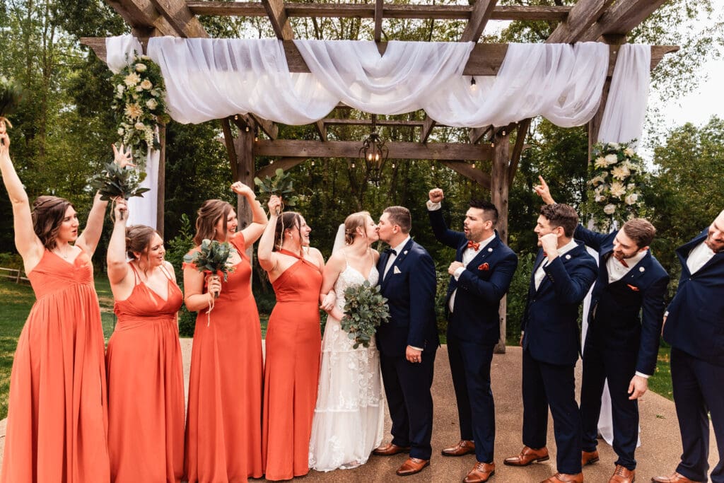 Wedding party posing beneath a rustic wooden pergola during a ceremony at The Barn at Ever Thine in Fenelton, PA