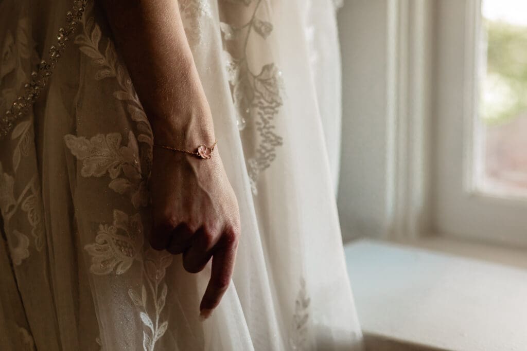 Close-up of bride’s bracelet as she holds her wedding dress during pre-ceremony preparations at Phipps Botanical Gardens