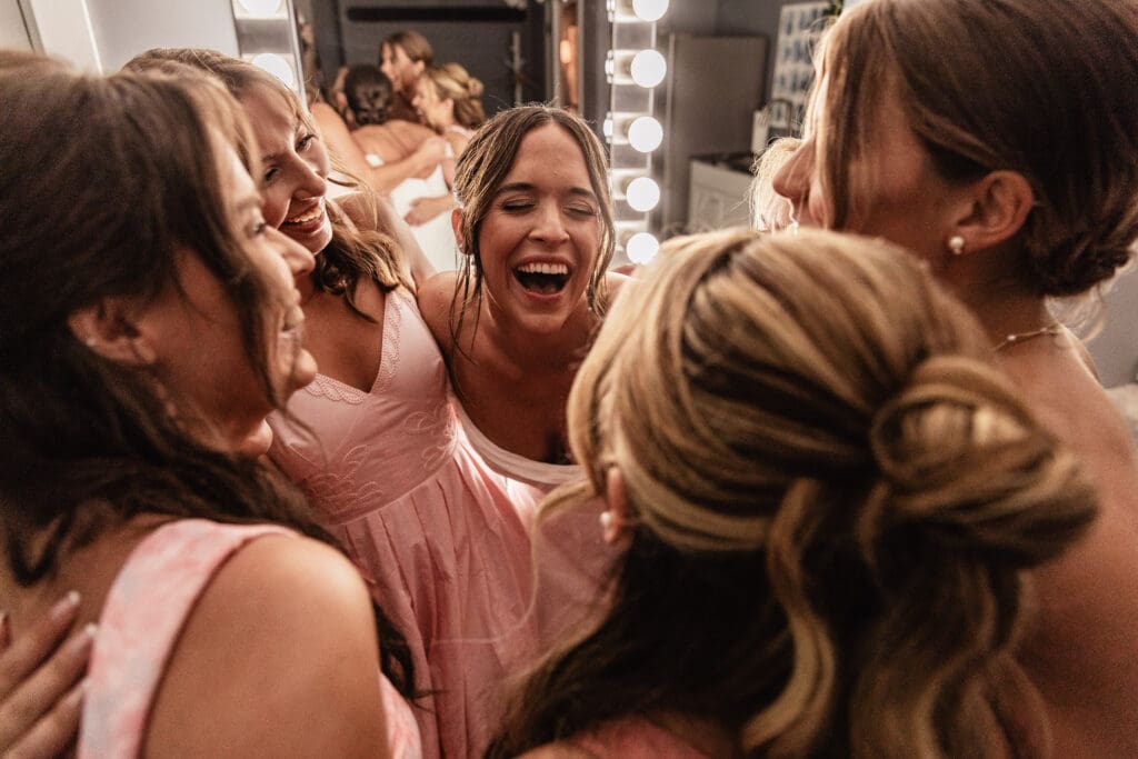 Bride laughing and hugging her bridesmaids in the Willowbrook bridal suite in Volant, PA