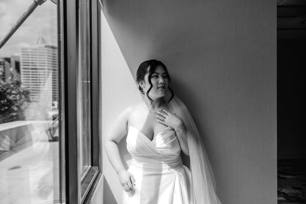 Black and white photo of bride standing near window at Sheraton Station Square