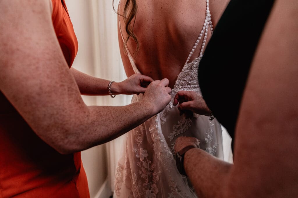 Mother and sister helping the bride into her wedding dress at The Barn at Ever Thine in Fenelton, PA